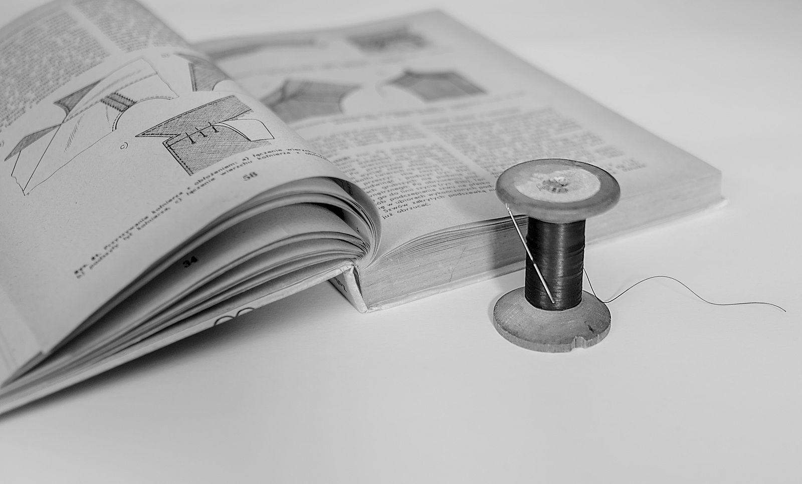 Książka o krawiectwie, szpulka nici z igłą