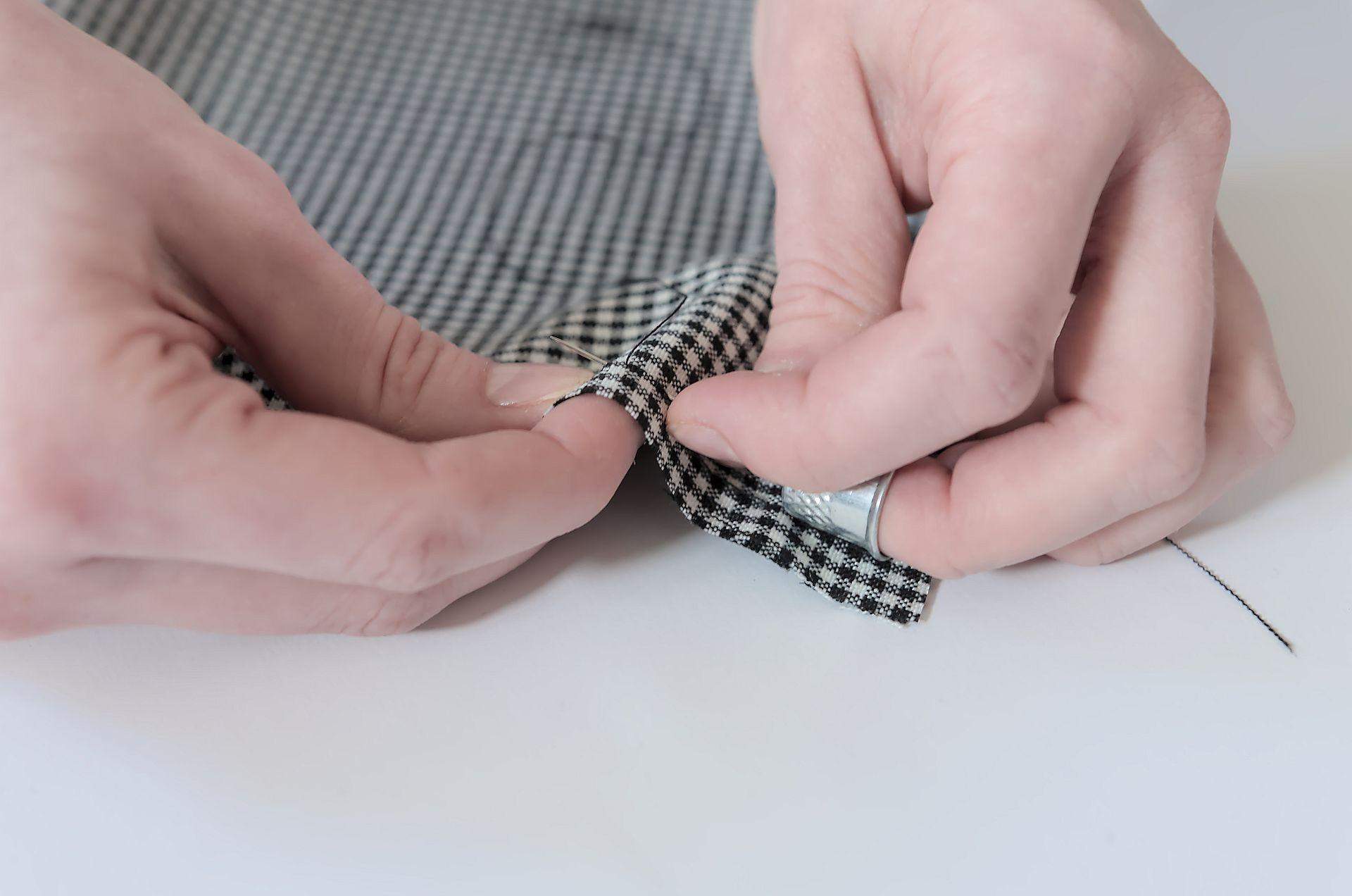 Szycie ręczne przy pomocy naparstka, tkanina czarno-biała, igła, nić