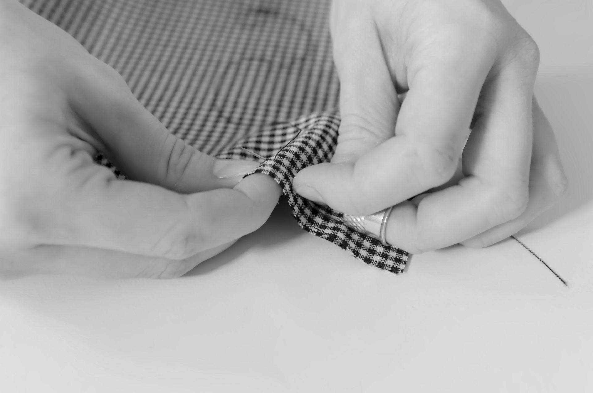 Szycie ręczne przy pomocy naparstka, tkanina czarno-biała, igła, nić